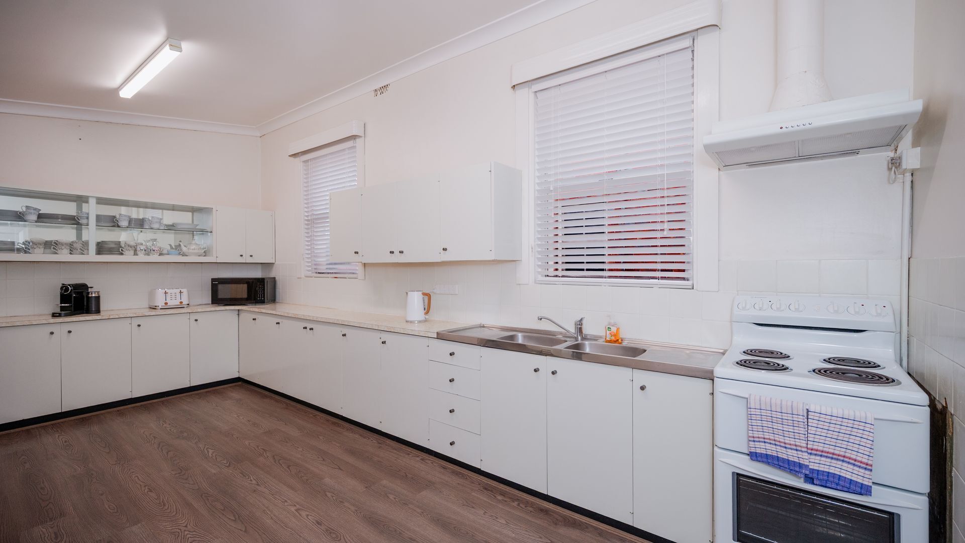 A kitchen with white cabinets, a microwave, a stove, and a sink.