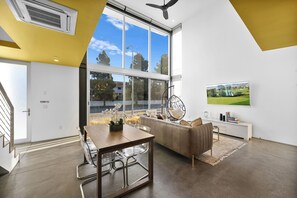 Een moderne woonkamer met een eethoek, grote ramen en uitzicht op de omgeving.
