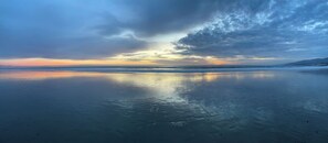 Een strand met een rustige zee en een zonsonderganglucht.