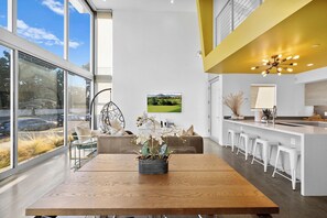Een moderne keuken met een centraal eiland, barstoelen en een groot raam met uitzicht op de omgeving.