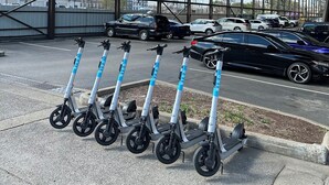 A covered parking area with electric scooters lined up and cars parked in the background. - Downtown Nashville Condo • 1 Mile to Broadway • Pool & Parking (Nashville)