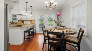 Une cuisine moderne avec des meubles blancs, un îlot central en bois et un coin repas comprenant une table ronde et des chaises.