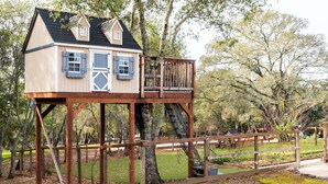 A wooden treehouse with a balcony, situated in a wooded area. - Glen Ellen Wine Country Retreat w/pool, hot tub, Bocce, tree-house & more (Glen Ellen)
