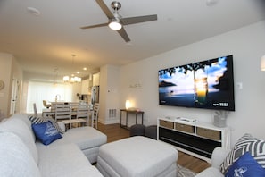 A modern living room with a flat-screen TV, a ceiling fan, and a dining area in the background. - Parking. Short Uber Ride. Townhouse in Annapolis! 3 Miles from USNA and Downtown (Annapolis)