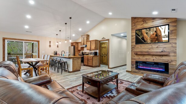 Una sala moderna con sofás de cuero, una mesa de futbolín y una chimenea.