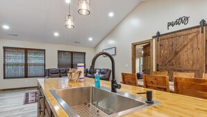 Una cocina con una isla grande, pileta de acero inoxidable, mesa de comedor de madera y sillas de cuero.