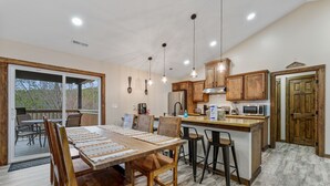 Una cocina amplia con armarios de madera, una isla central con taburetes de bar y una gran mesa de comedor con sillas.