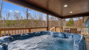 Un jacuzzi con terraza de madera y vista a árboles.