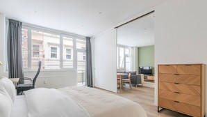 Ein modernes Hotelzimmer mit einem großen Bett, einem Schreibtisch, einem Stuhl und einem Kleiderschrank.