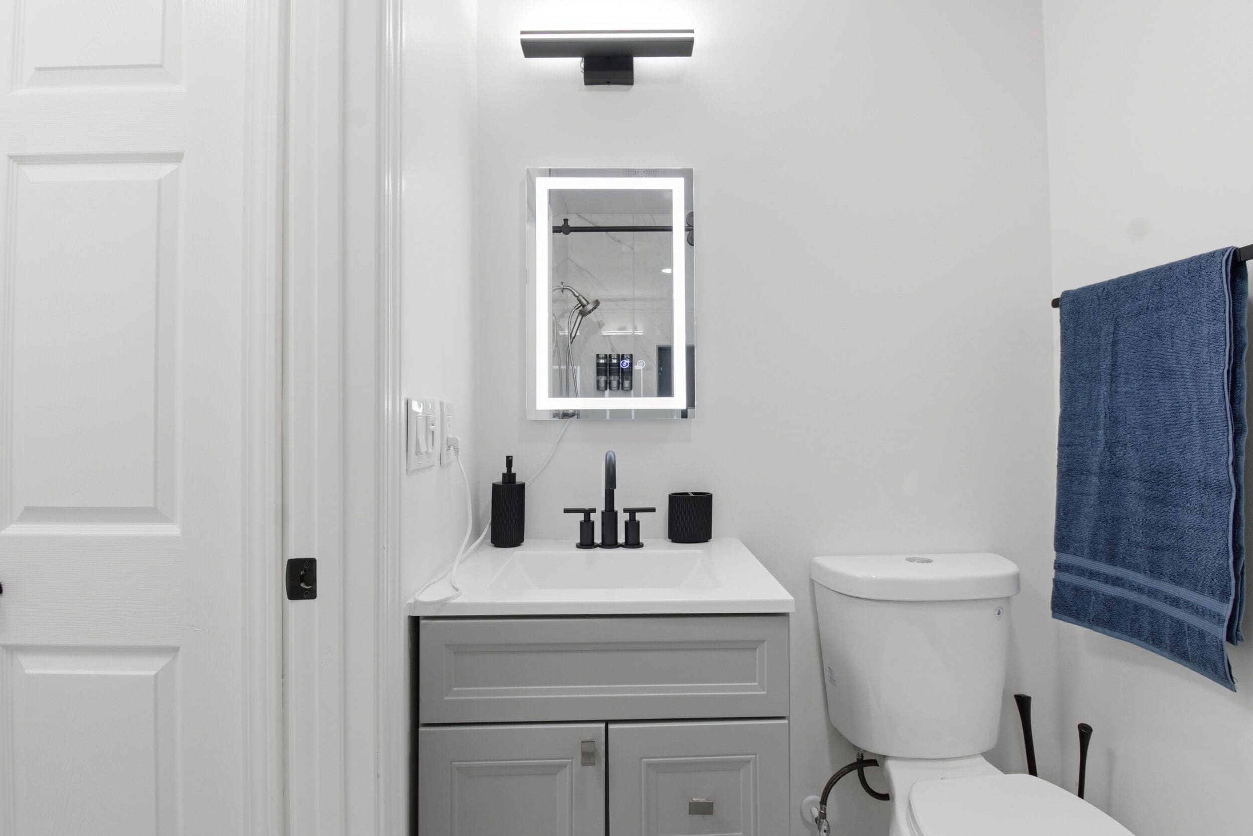 A bathroom with a white sink, mirror, and toilet.