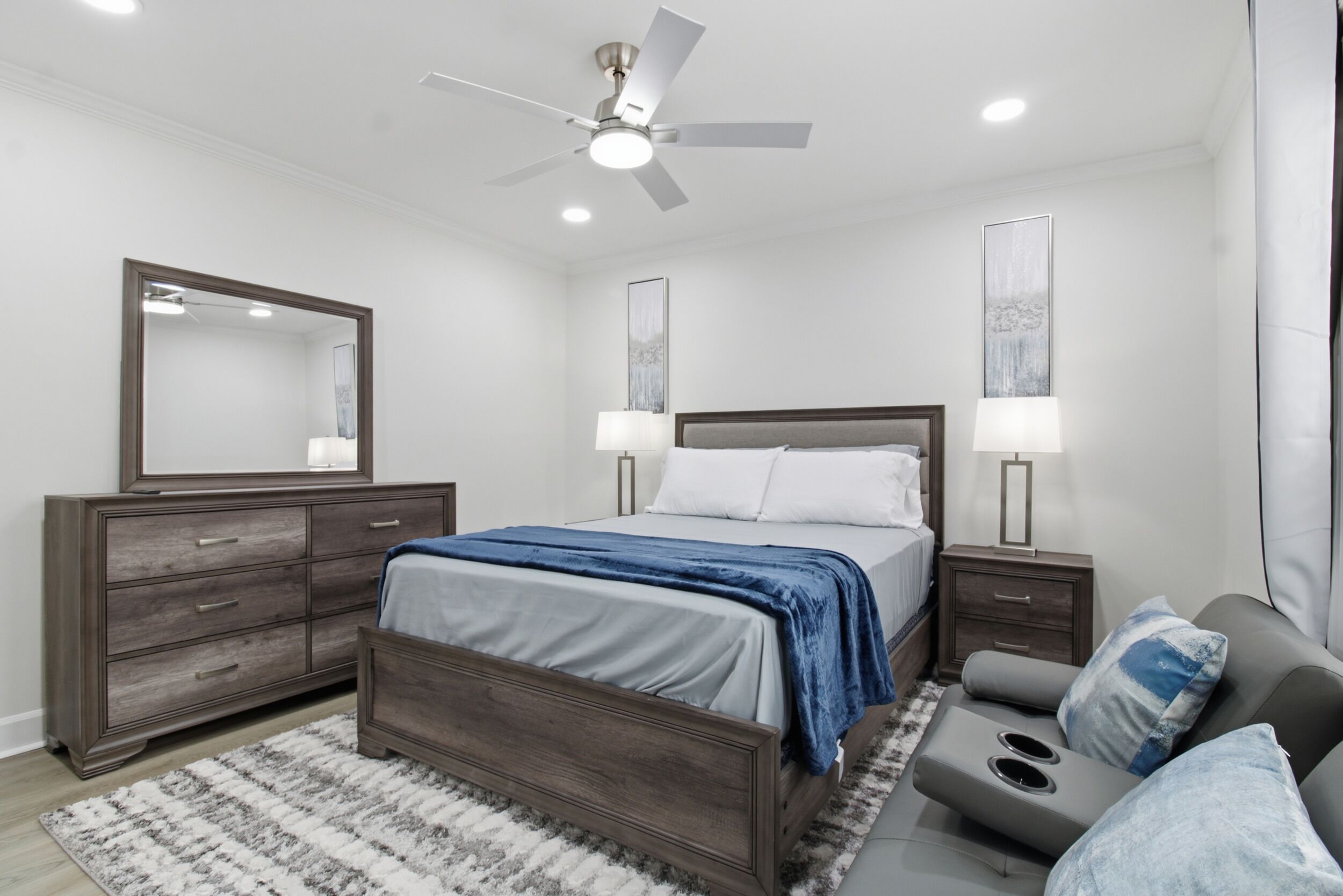 A bedroom with a bed, dresser, nightstands, and a ceiling fan.