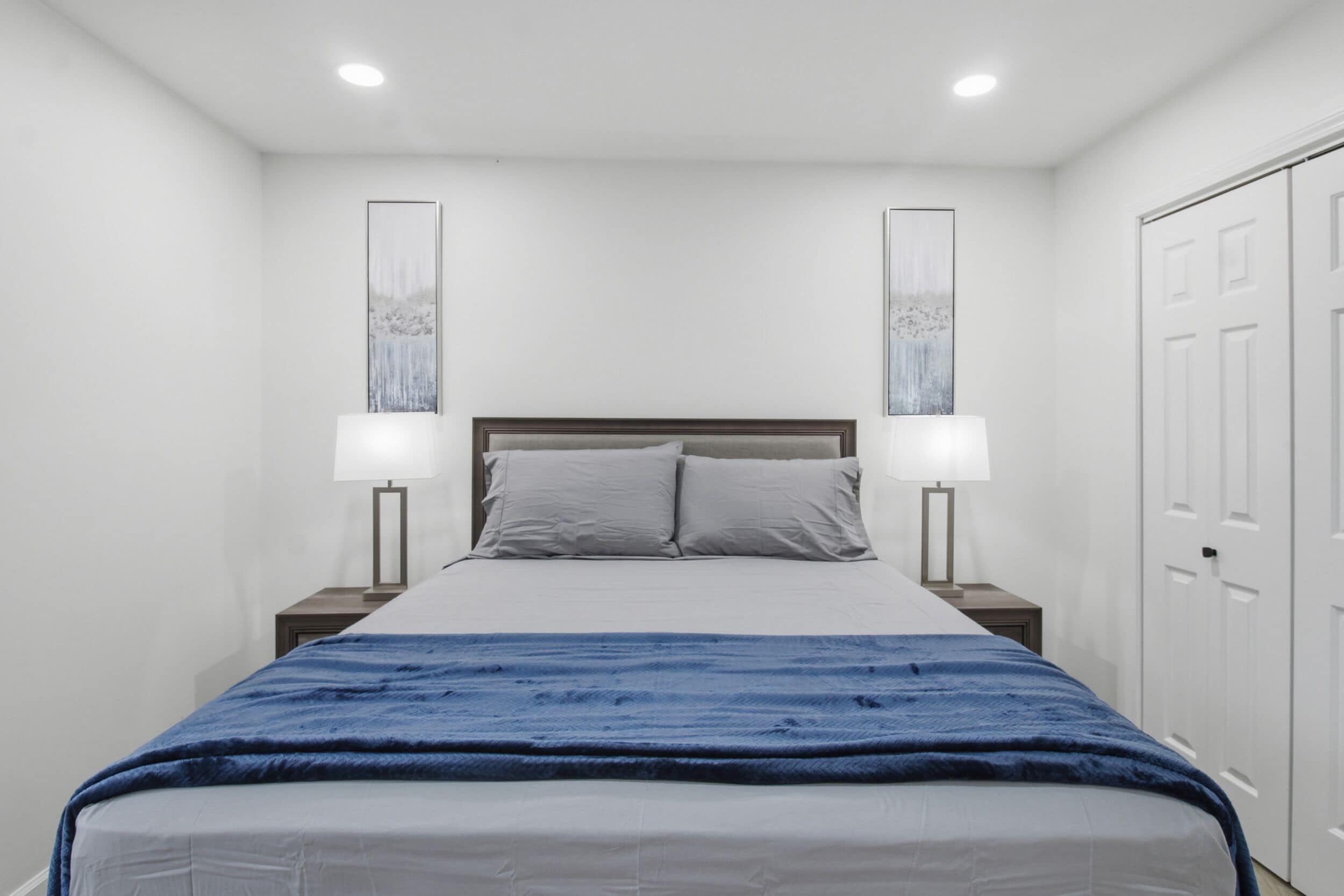 A bedroom with a bed, two bedside lamps, and a door.