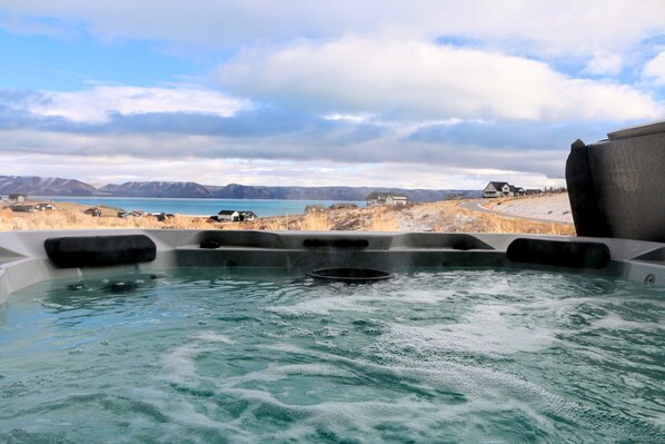A hot tub with a clear view of a lake and mountains in the background.