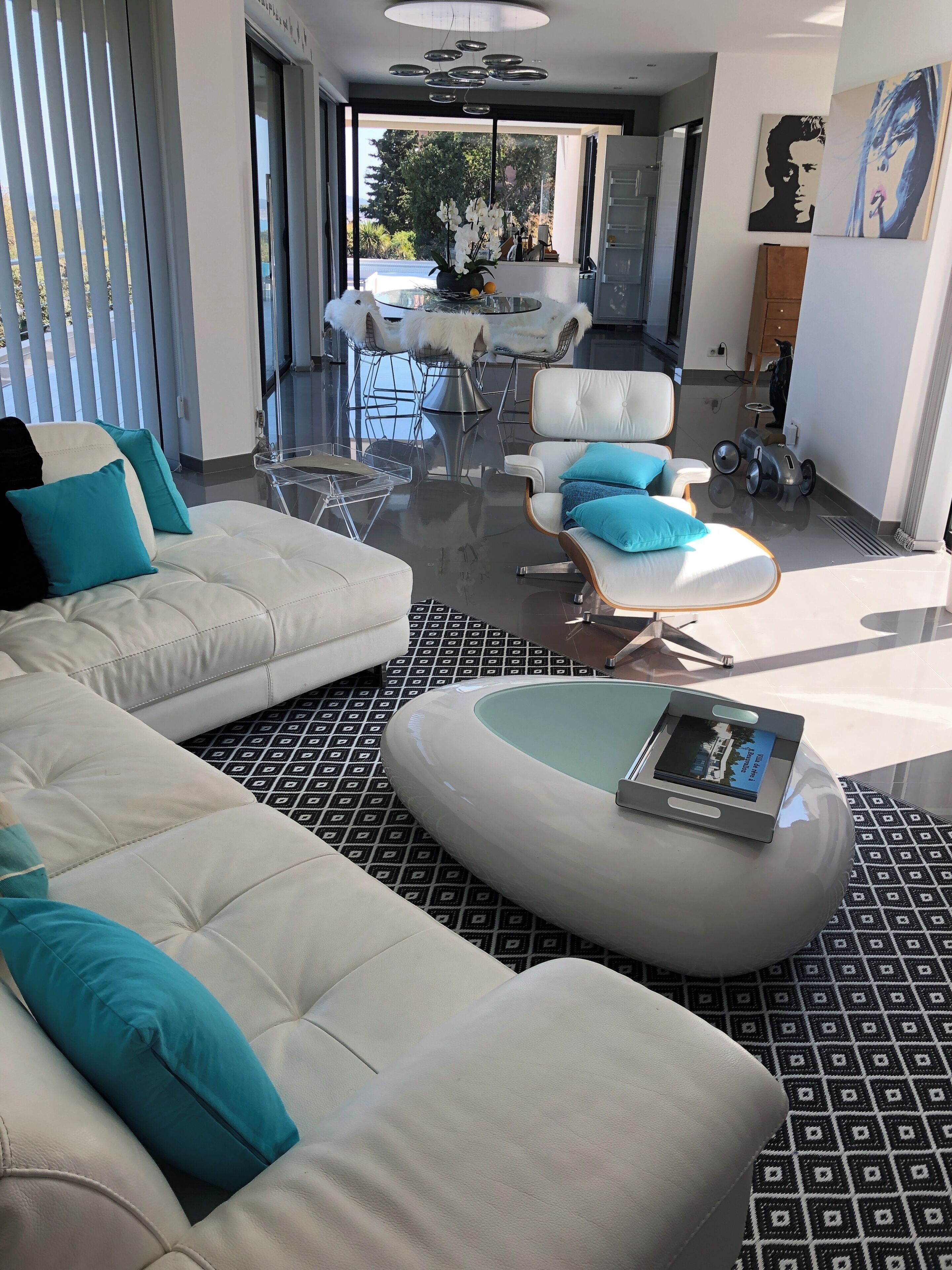 A modern living room with a white sofa, a round coffee table, and a glass dining table.