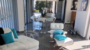 Een moderne woonkamer met een witte bank, een ronde salontafel en een glazen eettafel.