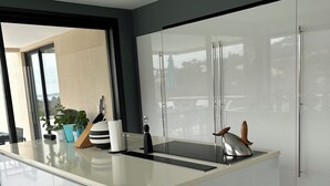 Een moderne keuken met een centraal eiland, witte kasten en een groot raam met uitzicht.