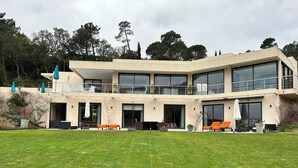 Een modern herenhuis met twee verdiepingen, grote ramen, een balkon en een verzorgd gazon.