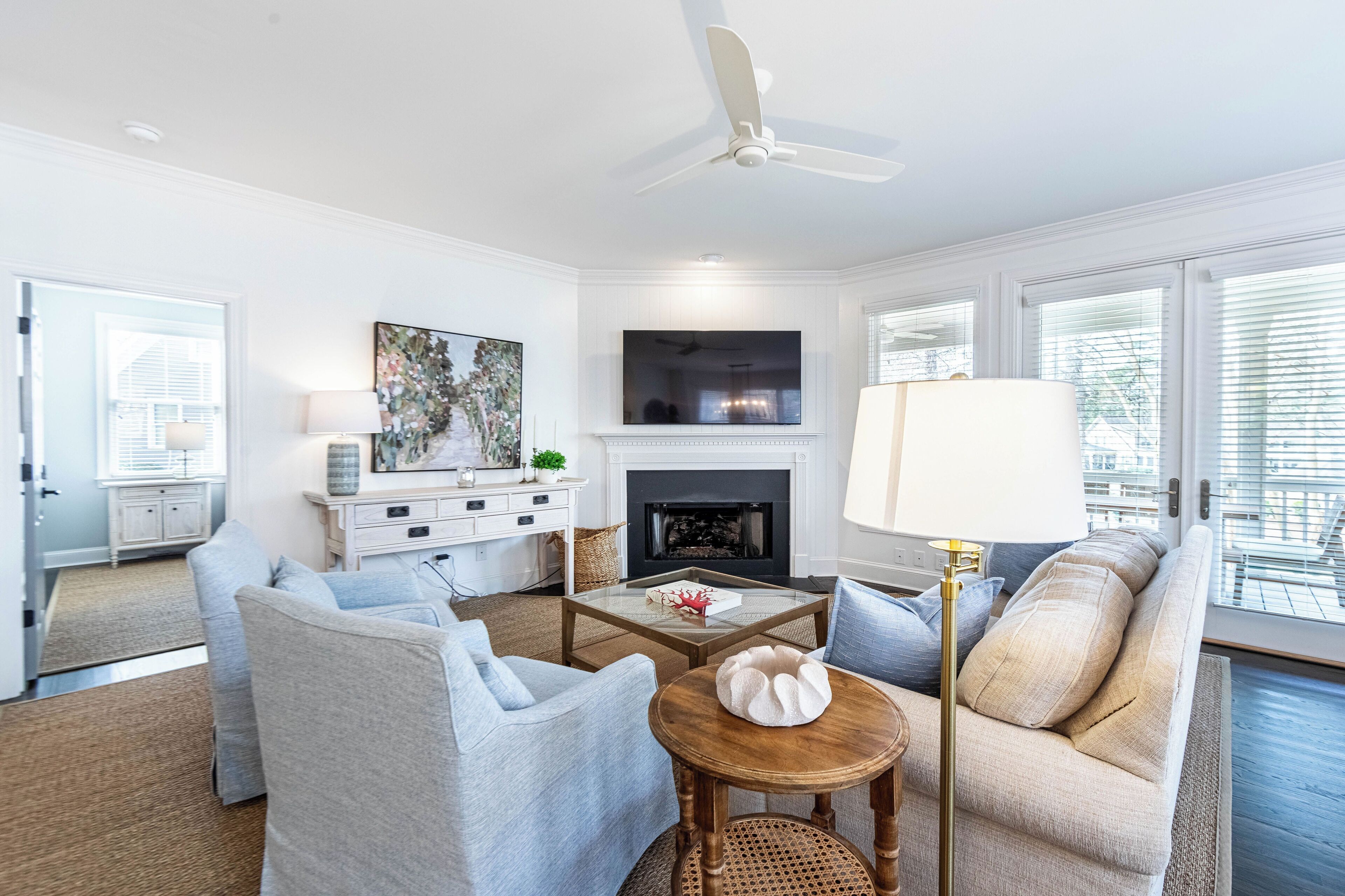 A modern living room with a fireplace, comfortable seating, and a large window.