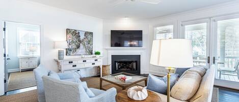 A modern living room with a fireplace, comfortable seating, and a large window.