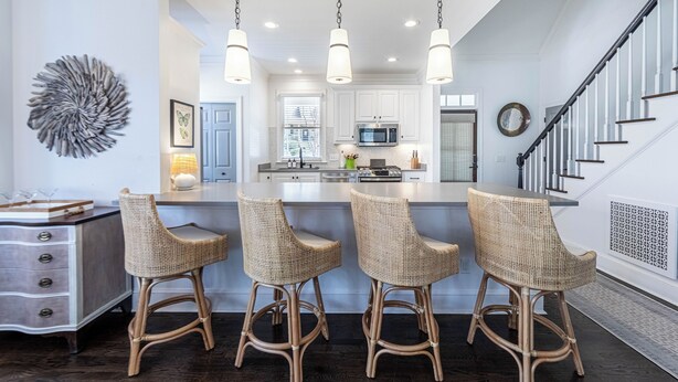 A modern kitchen with a central island, bar stools, and pendant lighting.
