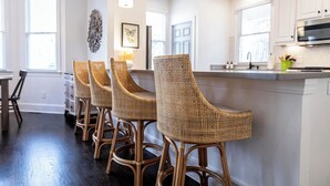 A kitchen with white cabinets, a central island with bar stools, and pendant lighting.