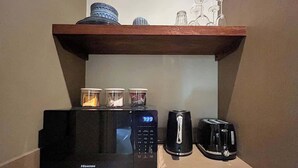 Un coin cuisine équipé d’un four à micro-ondes, d’un grille-pain et d’une machine à café, le tout posé sur un plan de travail.