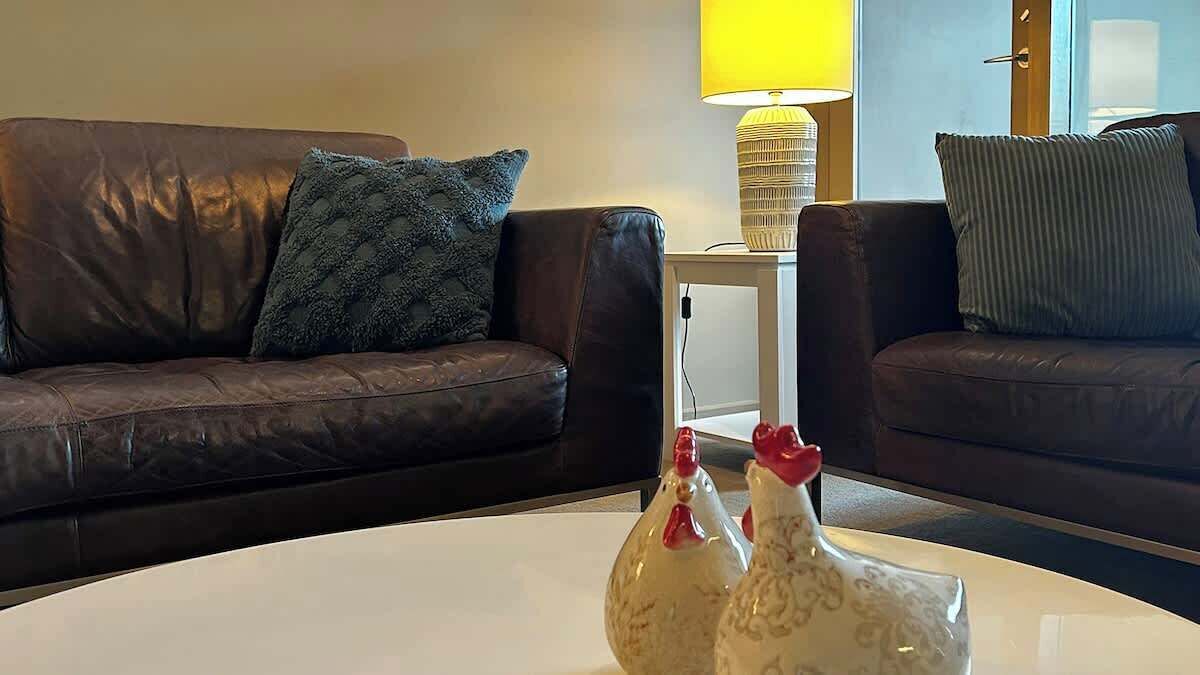 Een woonkamer met twee leren banken, een witte salontafel en een lamp.
