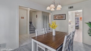 A dining area with a wooden table, white chairs, a vase with yellow flowers, and a chandelier. - Serene & Spacious Townhouse with Private Patio (Shreveport)