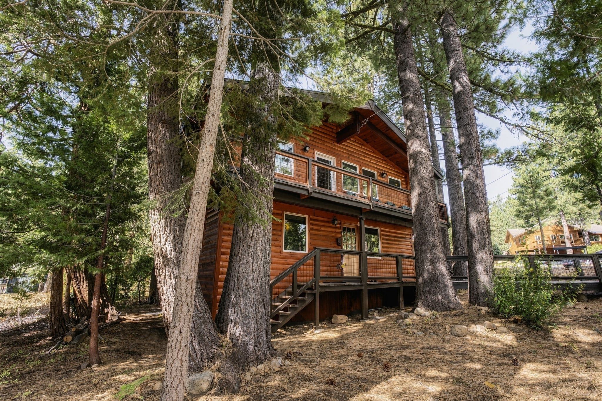 Eine zweistöckige Blockhütte mit Balkon, umgeben von hohen Kiefern.
