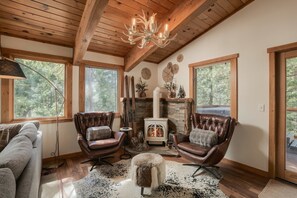 Une pièce chaleureuse avec une cheminée, des fauteuils en cuir et une grande fenêtre.