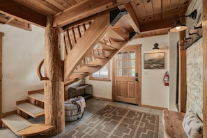 Un escalier en bois avec un banc intégré, une porte avec des panneaux de verre et un tapis sur le sol.