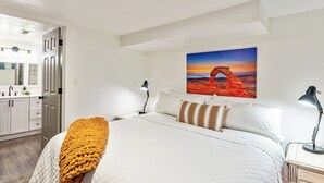A bedroom with a bed, a painting, a desk, and a nightstand. - Gather and Getaway!  3 bed 2 bath (Orem)