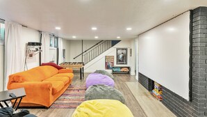 A modern living room with a sofa, bean bags, a staircase, and a fireplace. - Gather and Getaway!  3 bed 2 bath (Orem)