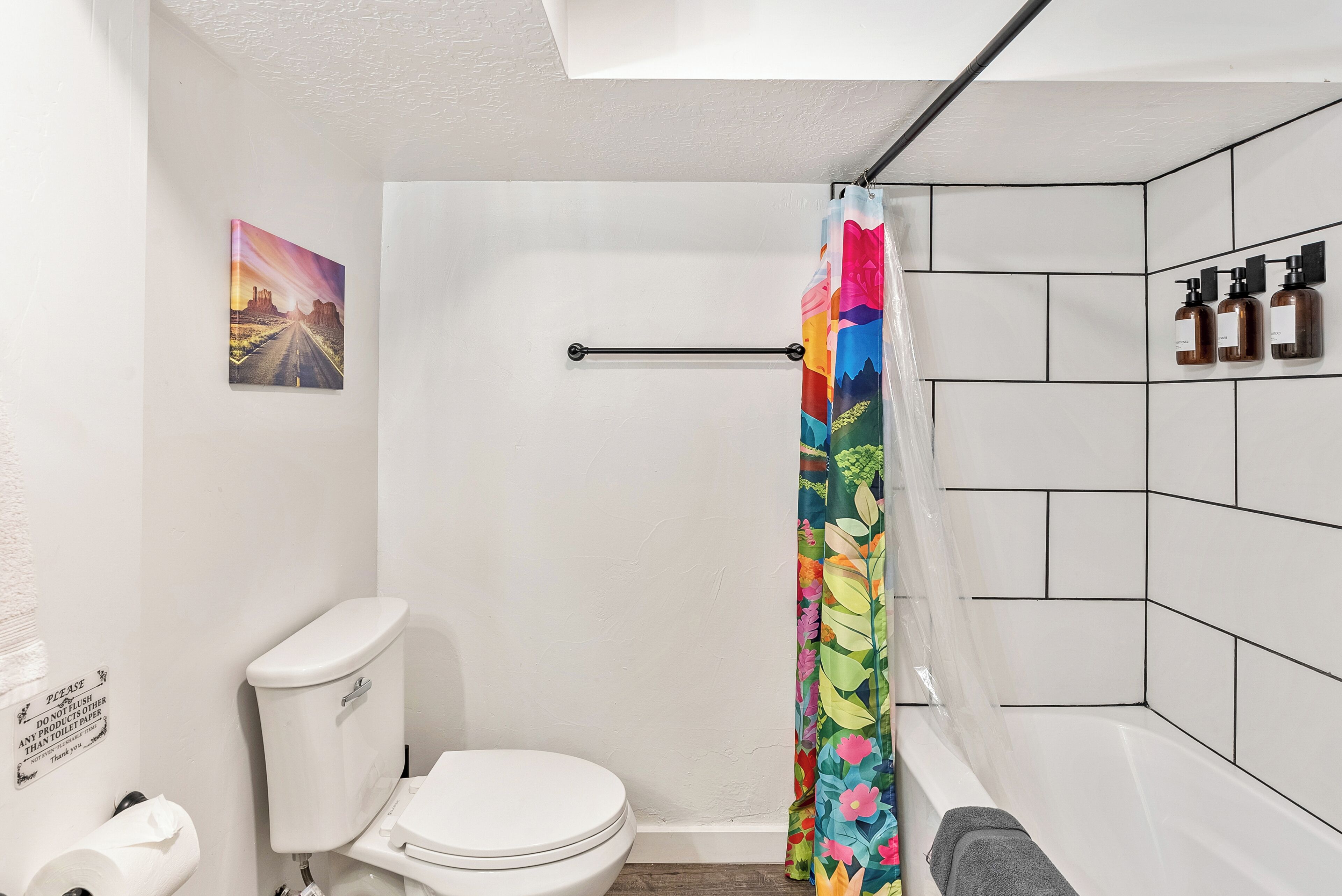 A bathroom with a shower curtain, toilet, and a wall-mounted soap dispenser.