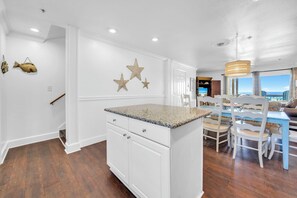 A kitchen with white cabinetry, a granite countertop, and decorative star wall art. - Gulf Front- Directly On The Beach- Sunchase 2A (Miramar Beach)