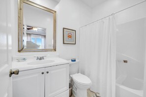 A bathroom with a white sink, toilet, and shower curtain. - Gulf Front- Directly On The Beach- Sunchase 2A (Miramar Beach)