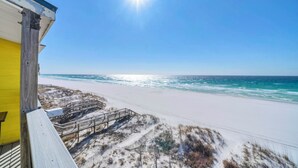 A beach view with a wooden deck and a yellow building. - Gulf Front- Directly On The Beach- Sunchase 2A (Miramar Beach)