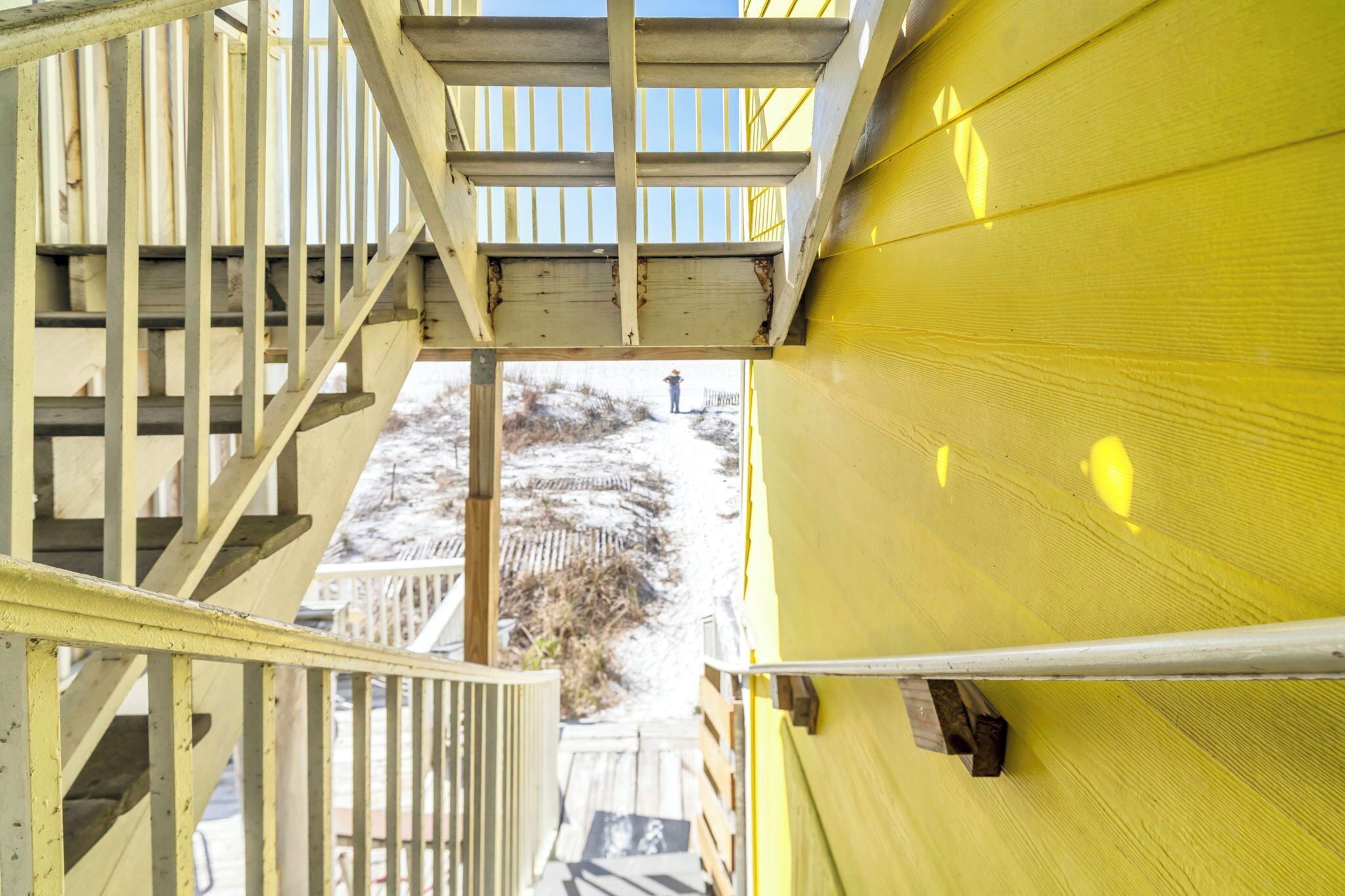 Eine Holztreppe führt zu einem gelben Gebäude mit Blick auf eine verschneite Landschaft.