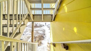 A wooden staircase leading to a yellow building with a view of a snowy landscape. - Honeymoon Studio* Directly On Sand* Sunchase 3B (Miramar Beach)