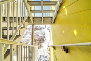 Un escalier en bois mène à un bâtiment jaune, d’où l’on peut admirer un paysage enneigé.