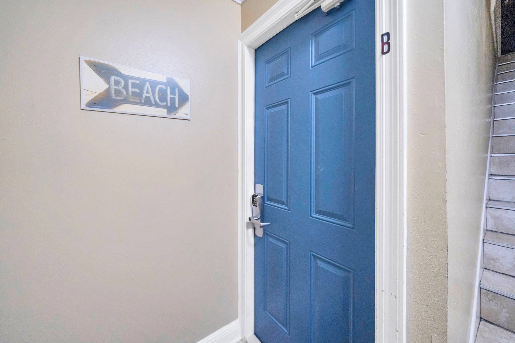 A blue door with a keyhole and a 'B' marking on the wall beside it.