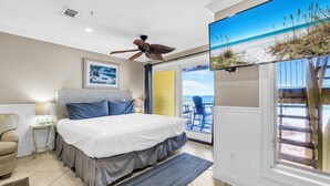 A bedroom with a large bed, a ceiling fan, a window with a view of the beach, and a chair. - Honeymoon Studio* Directly On Sand* Sunchase 3B (Miramar Beach)