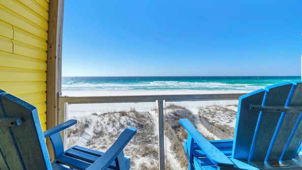 A beach view from a room with a window, featuring two blue chairs and a yellow wall. - Sunchase 7A - Directly On The Beach! Sleeps 8-Walk to Restaurants, AMAZING VIEWS! (Miramar Beach)