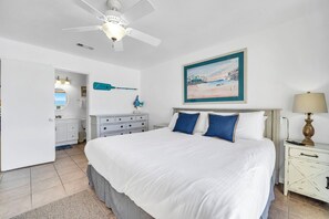 A bedroom with a large bed, a ceiling fan, a painting, and a nightstand with a lamp. - Sunchase 7A - Directly On The Beach! Sleeps 8-Walk to Restaurants, AMAZING VIEWS! (Miramar Beach)