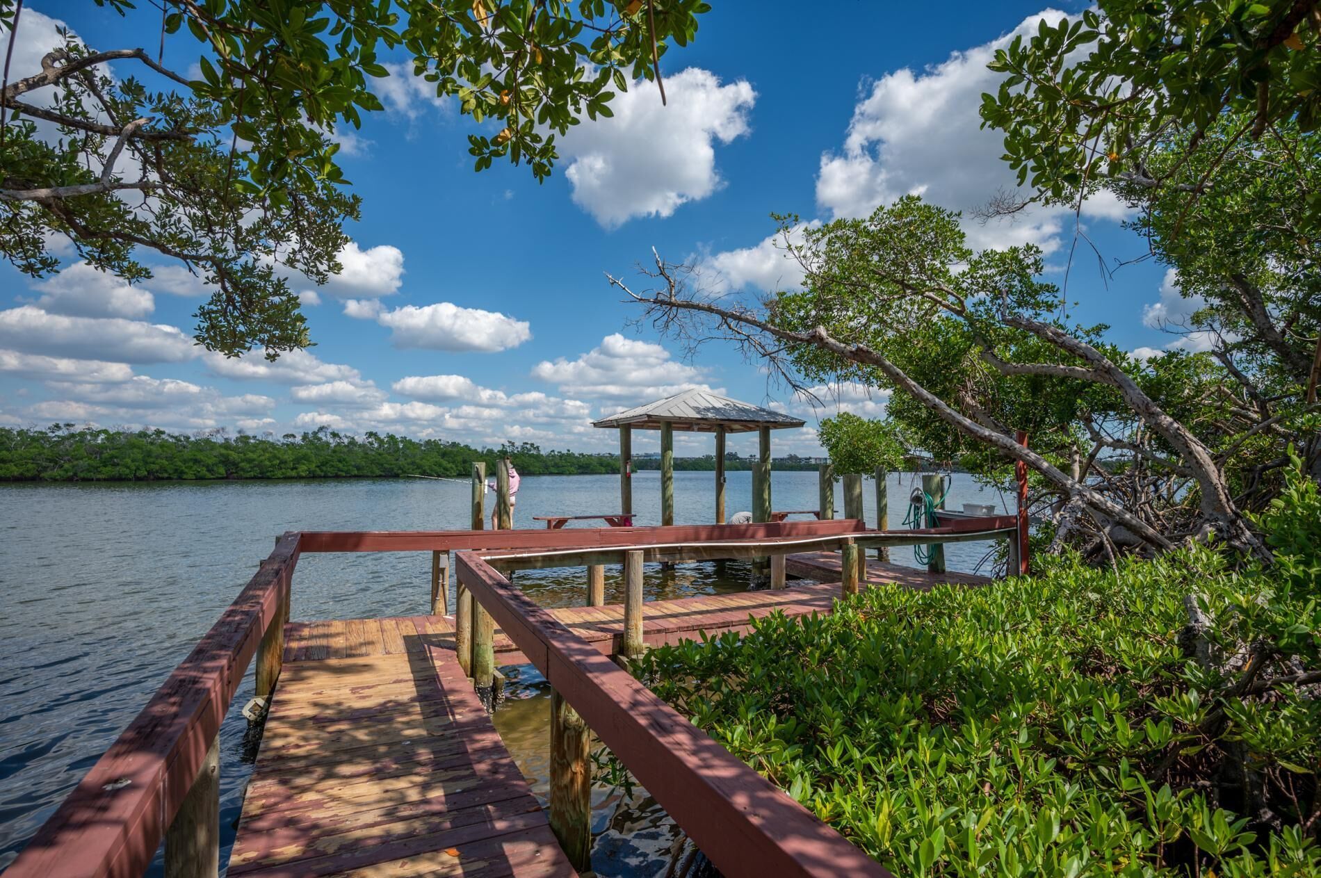 A wooden dock extending into a lake, with a gazebo on the far end.