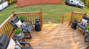 Terraza de madera con mobiliario exterior, incluyendo sillas y una mesa, rodeada por una barandilla de madera.