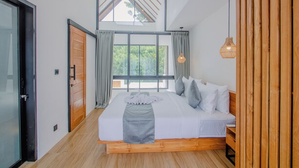 Une chambre à coucher avec un grand lit, une tête de lit en bois et un puits de lumière.