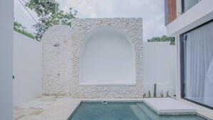 Un espace piscine extérieur moderne, agrémenté d’un mur en pierre et d’un banc intégré.