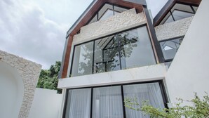 Un bâtiment moderne doté de grandes fenêtres, d’une façade en pierre et d’un toit en pente.