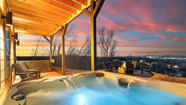 Un bain à remous avec une terrasse en bois et des chaises, offrant une vue panoramique magnifique au coucher du soleil.
